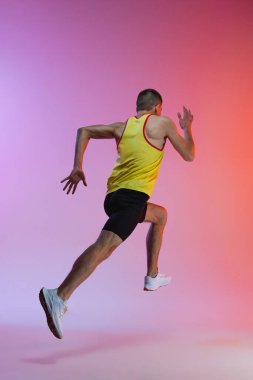 Gradyan stüdyo arka planında izole bir şekilde koşan genç erkek sporcunun arka plan portresi. Hareket halinde
