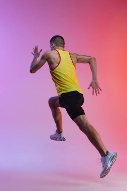 Gradyan stüdyo arka planında izole bir şekilde koşan genç erkek sporcunun arka plan portresi. Hareket halinde