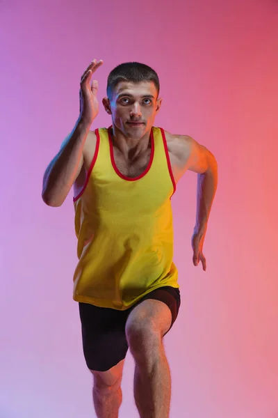 Retrato de jovem atleta masculino correndo isolado sobre fundo de estúdio gradiente. Em movimento — Fotografia de Stock