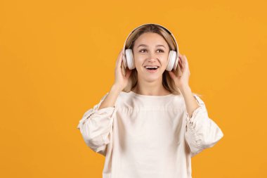 Kulaklıklı, sarı arka planda izole edilmiş güzel beyaz bir kızın kesilmiş portresi.