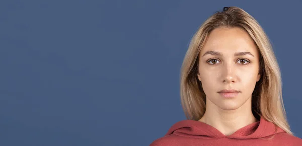 Ein schönes kaukasisches Mädchen posiert isoliert auf blauem Hintergrund. Ernster Gesichtsausdruck. Flyer — Stockfoto