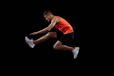 Genç adam, hareket halindeki erkek atlet, siyah stüdyo geçmişinden izole edilmiş. Yan görünüm