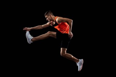 Genç adam, hareket halindeki erkek atlet, siyah stüdyo geçmişinden izole edilmiş. Yan görünüm