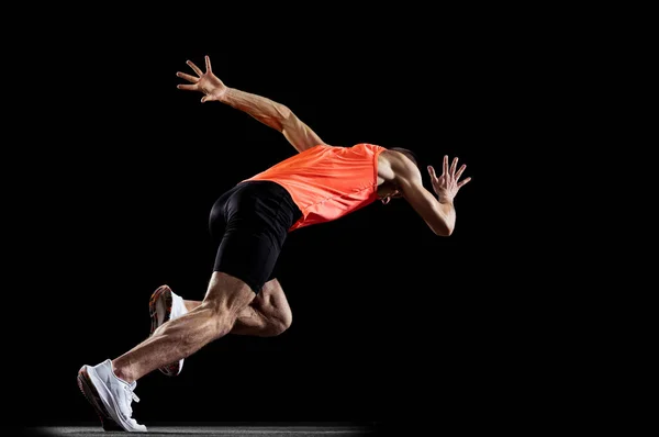 Full-length vista lateral retrato de jovem atleta profissional do sexo masculino corrida, formação isolada sobre fundo estúdio preto — Fotografia de Stock