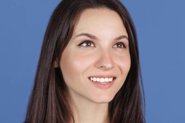 Mavi stüdyo arka planında izole edilmiş güzel bir kadının yakın plan portresi.