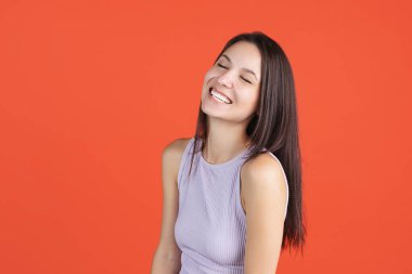 Güzel genç bir kadın gülümsüyor ve kırmızı stüdyo arka planında izole edilmiş poz veriyor.