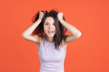 Kırmızı stüdyo arka planında izole edilmiş güzel bir genç kadının kesilmiş portresi. Huysuz kız.