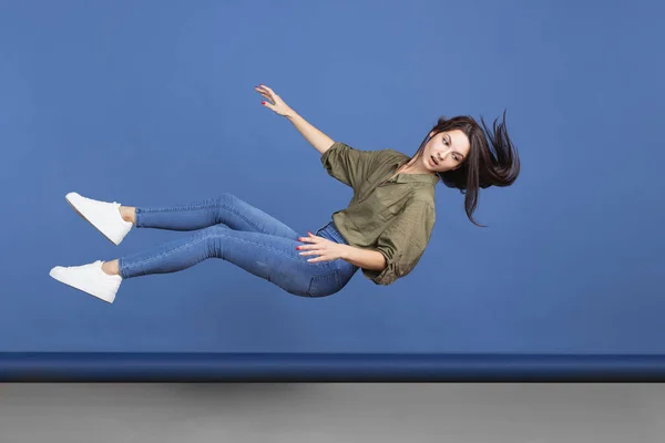 Imagen horizontal de longitud completa de una niña que cae aislada sobre un fondo azul. Levitación onírica — Foto de Stock