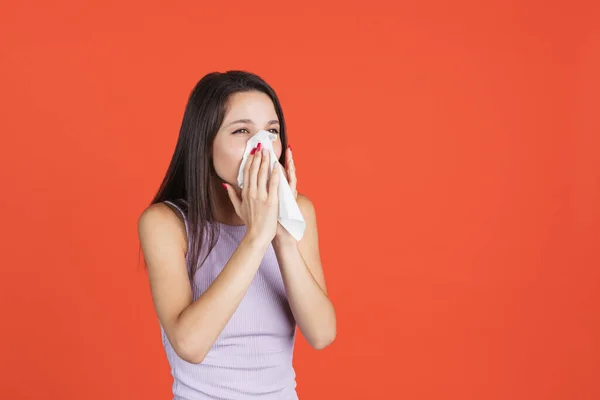 Een vrouwelijk model geïsoleerd over rode studi achtergrond. Niezen — Stockfoto