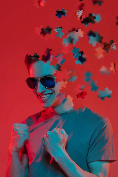 Creative collage of young caucasian man isolated over red background in neon light. Male head consist of puzzle pieces — Stock Photo, Image