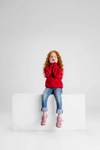 Portrait de petite fille avec une expression étonnante posant isolé sur fond de studio gris. — Photo