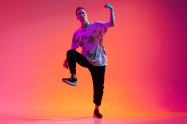 Bir enerjik genç adam hip-hop dansçısı eğitimi neon ışıklarıyla izole edilmiş.