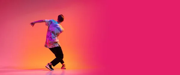 Achteraanzicht van jonge stijlvolle man dansende hiphop geïsoleerd over kleurrijke gradiënt achtergrond in neon licht. Vlieger — Stockfoto