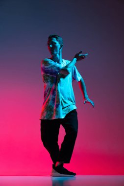 Genç adamın tam boy dikey portresi. Dans eden hip-hop. Gradyan pembe arkaplanda izole edilmiş.