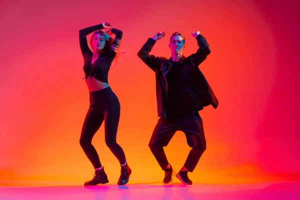 アクティブ若いです男と女ダンスヒップホップ孤立オングラデーションピンクスタジオ背景でネオンライト — ストック写真