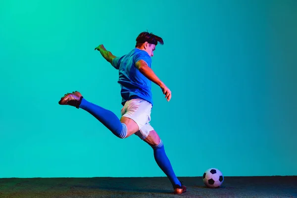 Retrato completo de un joven futbolista caucásico entrenando activamente aislado sobre fondo azul — Foto de Stock