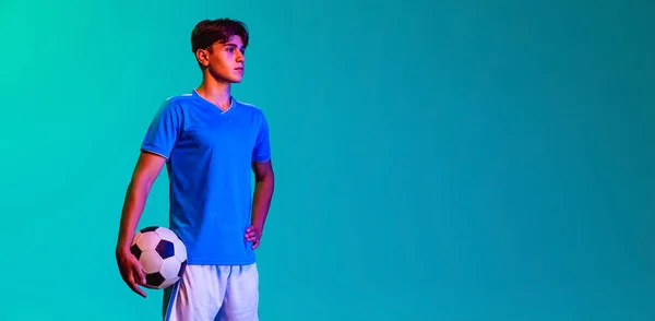 Retrato recortado de joven futbolista profesional aislado sobre fondo azul. Volante — Foto de Stock