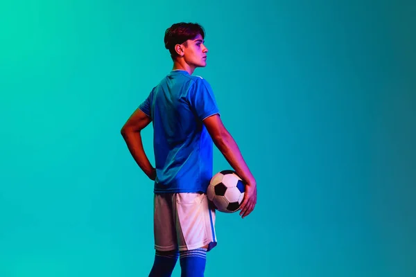Ritratto ritagliato di giovane calciatore professionista isolato su sfondo blu. Vista posteriore — Foto Stock