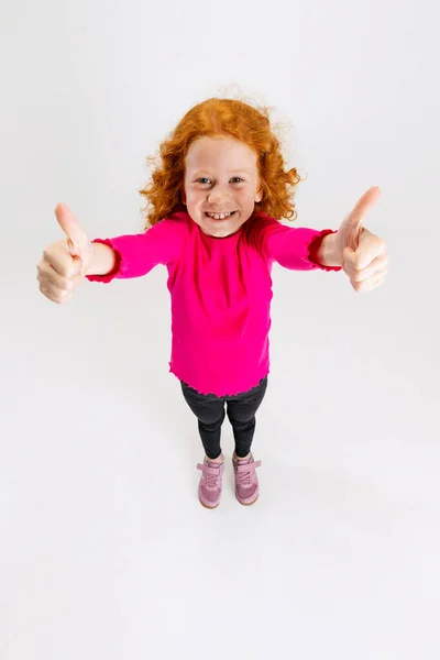 Portret małej rudej dziewczynki, dziecko w różowym swetrze pozowanie izolowane na białym tle studio. — Zdjęcie stockowe
