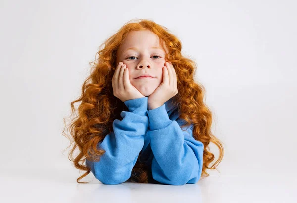 Portrait of little curly redheaded girl posing isolated over gray studio background. — Stock Photo, Image