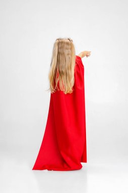 Beyaz stüdyo arka planında izole edilmiş süper kahraman gibi davranan küçük beyaz kızın arka plan portresi..