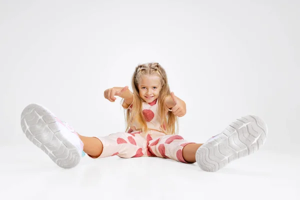 Portret van een blank meisje, kind dat geïsoleerd poseert over een witte studio achtergrond. Rustig zitten. — Stockfoto