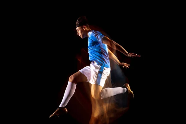 Młody sportowiec, trenujący piłkarza, odizolowany od czarnego tła w świetle mieszanym. Obrońca — Zdjęcie stockowe