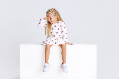 Küçük duygusal bir kızın portresi, beyaz stüdyo arka planında izole edilmiş bir çocuk..