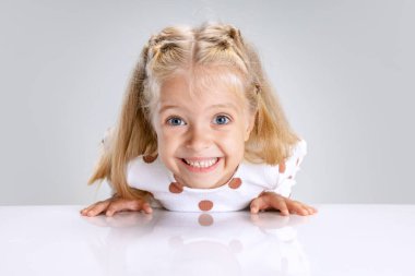 Beyaz stüdyo arka planında izole edilmiş küçük anaokulu kızının portresi. Heyecanlı çocuk