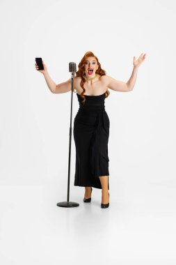 Beyaz arka planda izole edilmiş siyah elbiseli güzel bir kadının uzun bir portresi. Heyecanlı duygusal sanatçı.