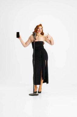 Beyaz arka planda izole edilmiş siyah elbiseli güzel bir kadının uzun bir portresi.