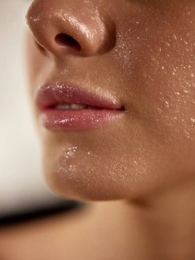 Close-up of wet glossy lips and fresh hydrated skin after skincare treatment. Concept of beauty, moisture, and healthy glow for cosmetics, skincare, and wellness advertising.