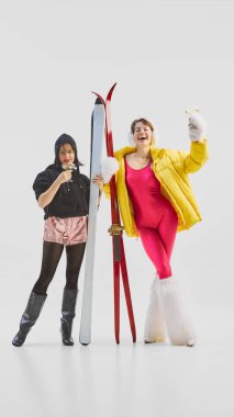 Two women celebrating winter fun in colorful ski fashion. Concept of friendship, winter leisure, and joyful apres-ski mood for lifestyle, fashion, and holiday advertising.