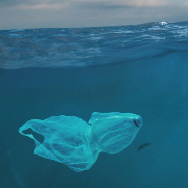 Plastic bag drifting under ocean surface symbolizing pollution. Concept of environmental awareness, ocean contamination, eco-education for sustainability and NGO initiatives.
