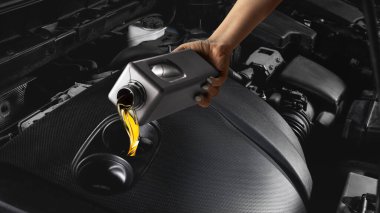 Tamirci araba bakım prosedürü sırasında motora altın motor yağı döküyor. Otomotiv hizmeti, kayganlaştırıcı teknolojisi ve performans optimizasyonu için profesyonel bakım kavramı.