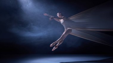 Yumuşak mavi sahne ışıklarının altında kumaşa sarılı bir balerin. Yaratıcı ve editoryal projeler için performans sanatı, beden kontrolü ve hareket tekniği kavramı.