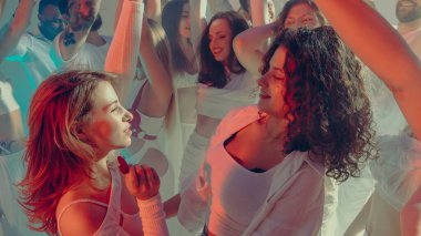 Sevgililer Günü partisinin yumuşak beyaz ışığında gülümseyen arkadaşlar birlikte dans ediyorlar. Şık şenlik ortamında gençlik özgürlüğü, dostluk ve duygusal bağ kavramı.