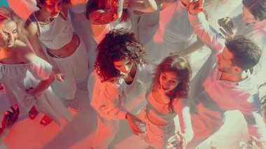 Neon ışıklı kulüpteki şenlik partisinde kadınlar ve erkekler enerjiyle yakın dans ediyorlar. Yaşam tarzı ifadesi kavramı, toplu kutlamalarda neşe ve sosyal ve dijital kültür için sanatsal görseller.