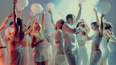 Beyaz kıyafetler içinde şampanya ve balonlarla kutlama yapan bir grup şık insan. Neşeli atmosfer, dostluk sevinci, aşk kutlaması ve modern parti yaşam tarzı kavramı.