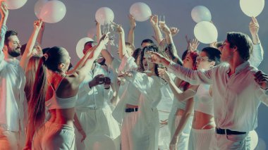 Beyaz sevgililer günü partisini kutlayan neşeli kalabalık birlik içinde kadehler kaldırıyor. Paylaşılan mutluluk kavramı, modern kutlama kültürü ve duygu yoluyla sosyal bağlantı..