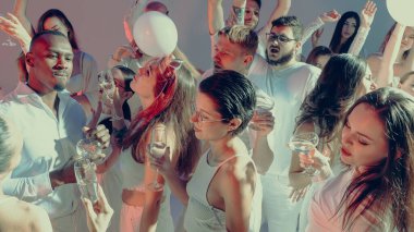 Bir grup arkadaş, neşeli ışıklar altında beyaz kıyafetler içinde enerjik dans partisinin tadını çıkarıyorlar. Tatil ve kutlama kavramı, yaşam tarzı eğlencesi ve müzikte duygusal özgürlük..