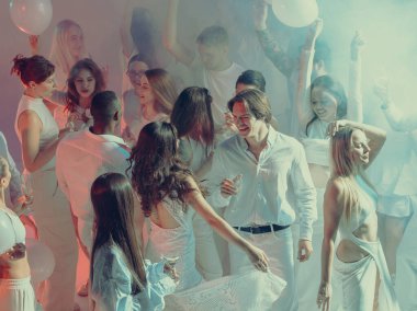 Beyaz ışıkta dans eden neşeli kalabalık aşkı, dostluğu ve yaratıcı özgürlüğü kutluyor. İlişkiler ve duygular kavramı, yaşam tarzı kutlaması ve hareket yoluyla sanatsal ifade.