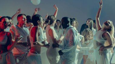 Parlak etkinlik ışıkları altında ritim içinde dans eden neşeli kalabalık. Gece hayatı kutlamaları, gençlik duyguları ve modern kültürün kolektif ruhu..