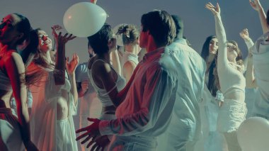 Beyaz Sevgililer Günü gecesinde balonlarla özgürce dans eden gençler. Tasasız neşe kavramı, modern kutlama, ve gece hayatında duygusal birliktelik..