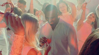 Sevgililer Günü partisinde neşeli arkadaşlarla romantik anlar yaşayan bir çift. Duygusal ilişkiler kavramı, şenlikli yaşam tarzı kültürü, etkinlik ve aşk kampanyaları için reklam.