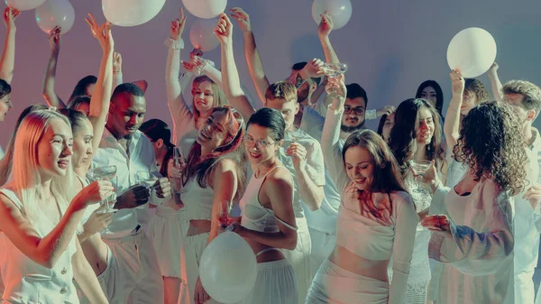 Beyaz bir partide dans eden bir grup insan arkadaşlığı ve enerjiyi kutluyor. Tatil kavramı ve şenlik etkinlikleri, güzel içecekler ve modern etkinlik tanıtımı..