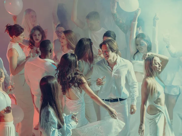 Beyaz ışıkta dans eden neşeli kalabalık aşkı, dostluğu ve yaratıcı özgürlüğü kutluyor. İlişkiler ve duygular kavramı, yaşam tarzı kutlaması ve hareket yoluyla sanatsal ifade.