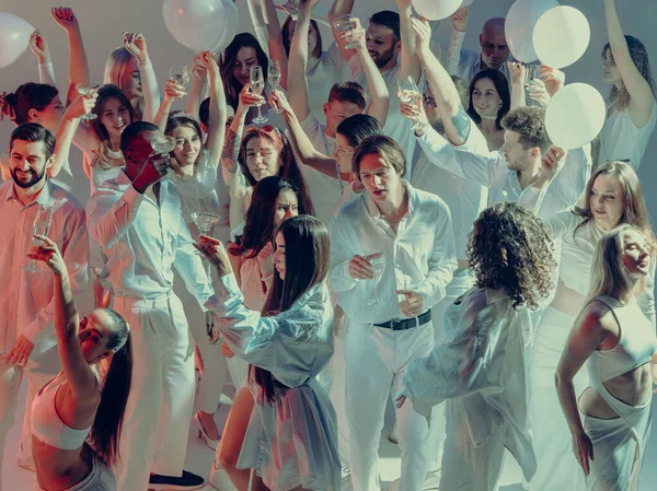 Beyaz kutlamalarda parlak ışık ve şenlik enerjisi altında kadehleri kaldıran arkadaşlar. Alkol ve içecek kavramı, etkinlik tanıtımı ve paylaşılan bağlantı yoluyla psikolojik mutluluk.