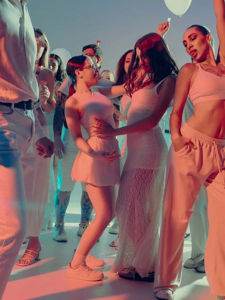 Parlayan Sevgililer Günü partisinde yüzyüze dans eden neşeli kadınlar. Modern olay kutlaması kavramı, LGBTQ, ve canlı gece atmosferinde duygusal özgürlük.