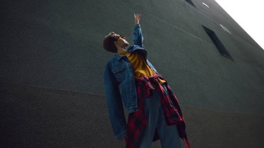 Kot pantolonlu ve sarı kıyafetli bir adam yüksek binanın yakınına uzanıyor. Yaşam tarzı, eğitim terfisi, yaratıcı öğrenme, kentsel iletişim ve görsel kimlik motivasyonu kavramı.